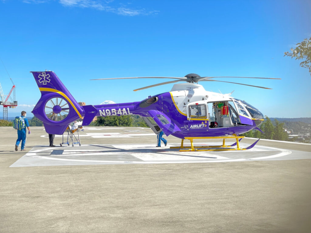 Airlift Northwest helicopter on a hospital helipad with crew members nearby